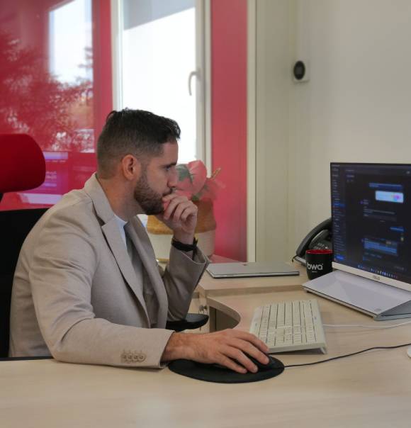 Homme concentré travaillant sur un ordinateur dans un bureau moderne, illustrant la communication professionnelle.