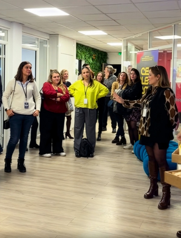 Groupe de personnes en réunion ou formation dans un espace moderne avec des plantes et affiches promotionnelles.